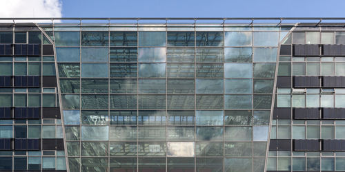 Low angle view of glass building against sky