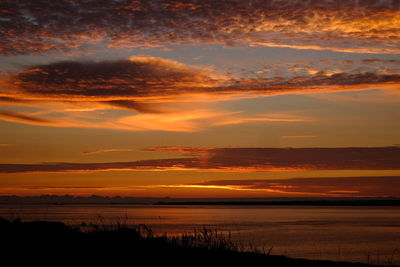 Scenic view of dramatic sky over silhouette landscape during sunset