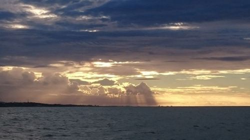 Sunlight streaming through clouds over sea