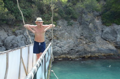 Full length of shirtless man standing on rock