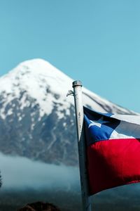 Low angle view of flag on snowcapped mountain against sky