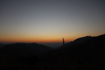 Scenic view of silhouette mountains against clear sky during sunset