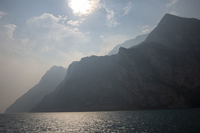 Scenic view of sea by mountains against sky