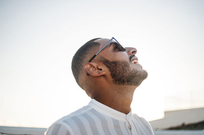 Close-up of young man wearing sunglasses standing against sky