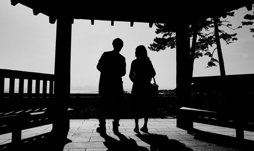 Rear view of silhouette men and women standing against clear sky