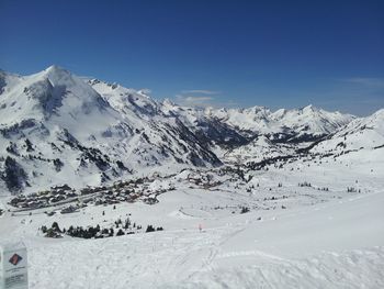 Scenic view of snow covered mountains against clear blue sky