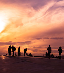 Silhouette people at rooftop against sky during sunset