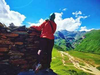 Rear view of man standing on mountain against sky