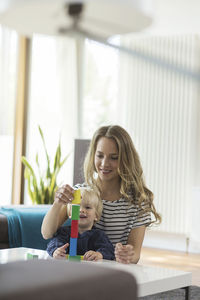 Mother and son stacking building bricks in living room