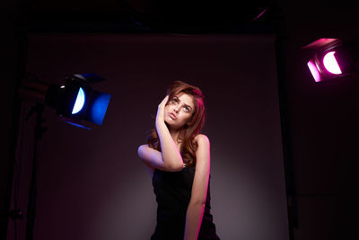 Portrait of young woman standing against wall