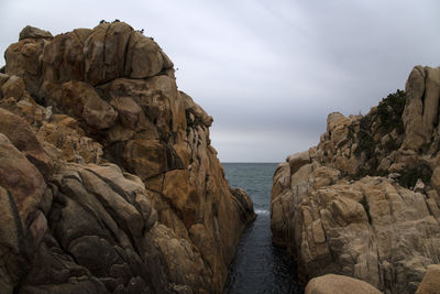 Rock formations by sea against sky