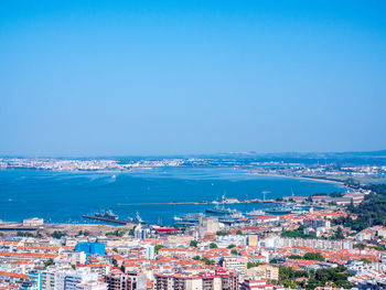 High angle view of cityscape by sea against clear sky