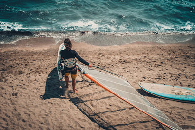 Rear view of person with windsurf board at beach