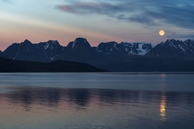 Scenic view of lake by mountains against sky during sunset