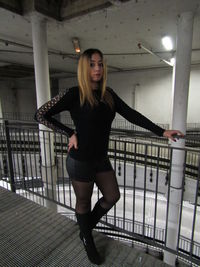 Portrait of young woman standing on railing