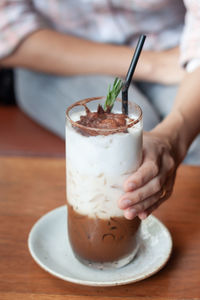 Midsection of person holding drink on table