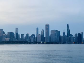 Sea by buildings against sky in city