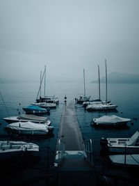 Sailboats moored in sea against sky