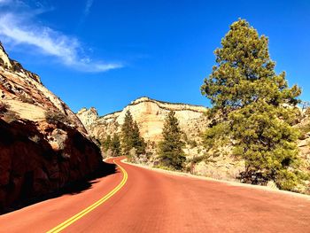 Road amidst mountains against blue sky