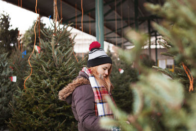 Side view of woman looking at christmas trees