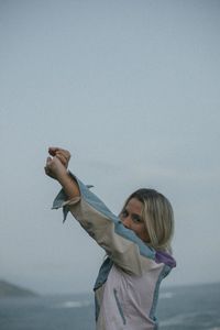 Rear view of woman with arms raised against clear sky