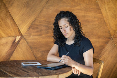 Woman using a digital tablet while sitting at a table.