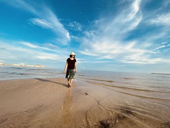 Woman walking on beach against sky