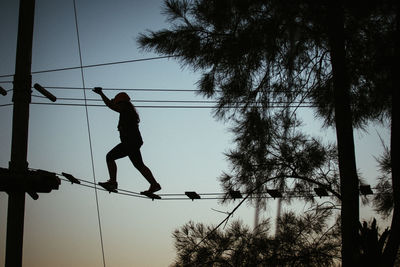 Low angle view of silhouette girl jumping against clear sky