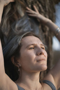 Close up adult genuine woman with ruffled hair posing near tree portrait picture