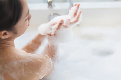 Rear view of young woman taking bath in bathtub