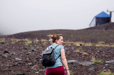 Rear view of woman walking on field against sky