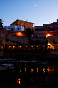 Illuminated buildings by lake at night