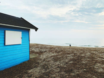 Beach hut by sea against sky