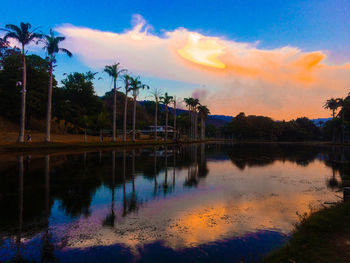 Scenic view of lake by trees against sky at sunset