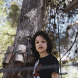 Portrait of teenage boy standing against tree