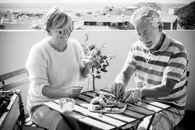 Senior couple having food while sitting in balcony