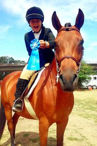 Portrait of boy riding horse on field against sky