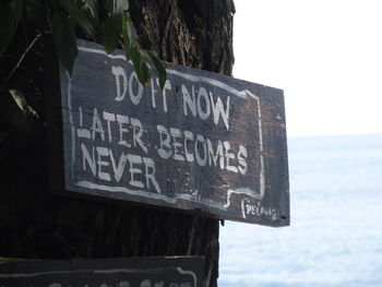 Close-up of information sign against sea