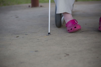 Low section of blind man with cane walking on road