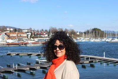 Portrait of woman with curly hair standing by sea