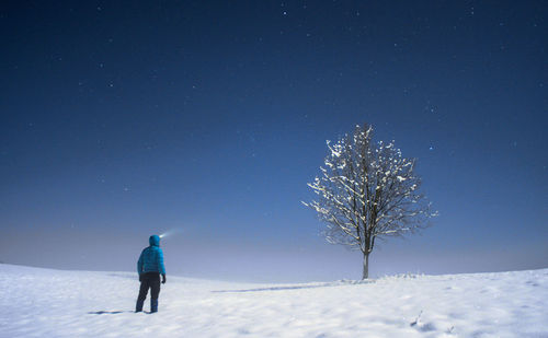 Rear view of person on snow covered field against sky