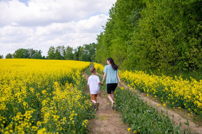 Rear view of woman walking on field against sky