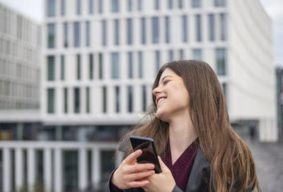 Young woman using mobile phone in city