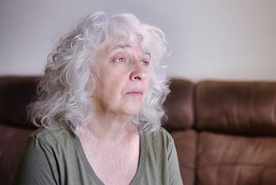 Portrait of an elderly gray-haired curly lady with long hair.