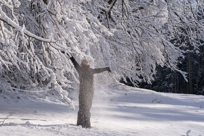 Young woman enjoying winter under snow covered tree