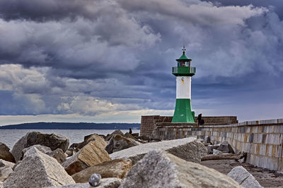 Lighthouse by sea against sky