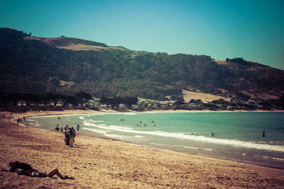 People on beach against clear sky
