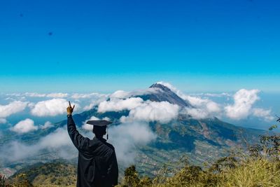 Rear view of man looking at mountain against sky