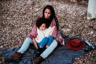 Smiling daughter sitting with mother on land