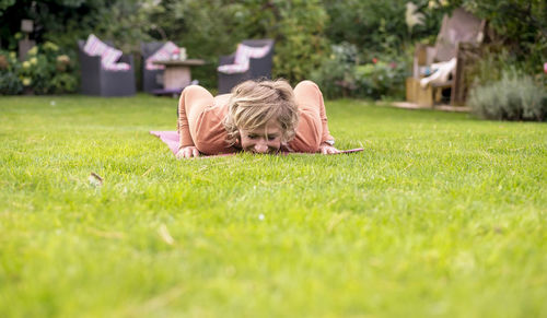 Mature woman exercising on grass at lawn